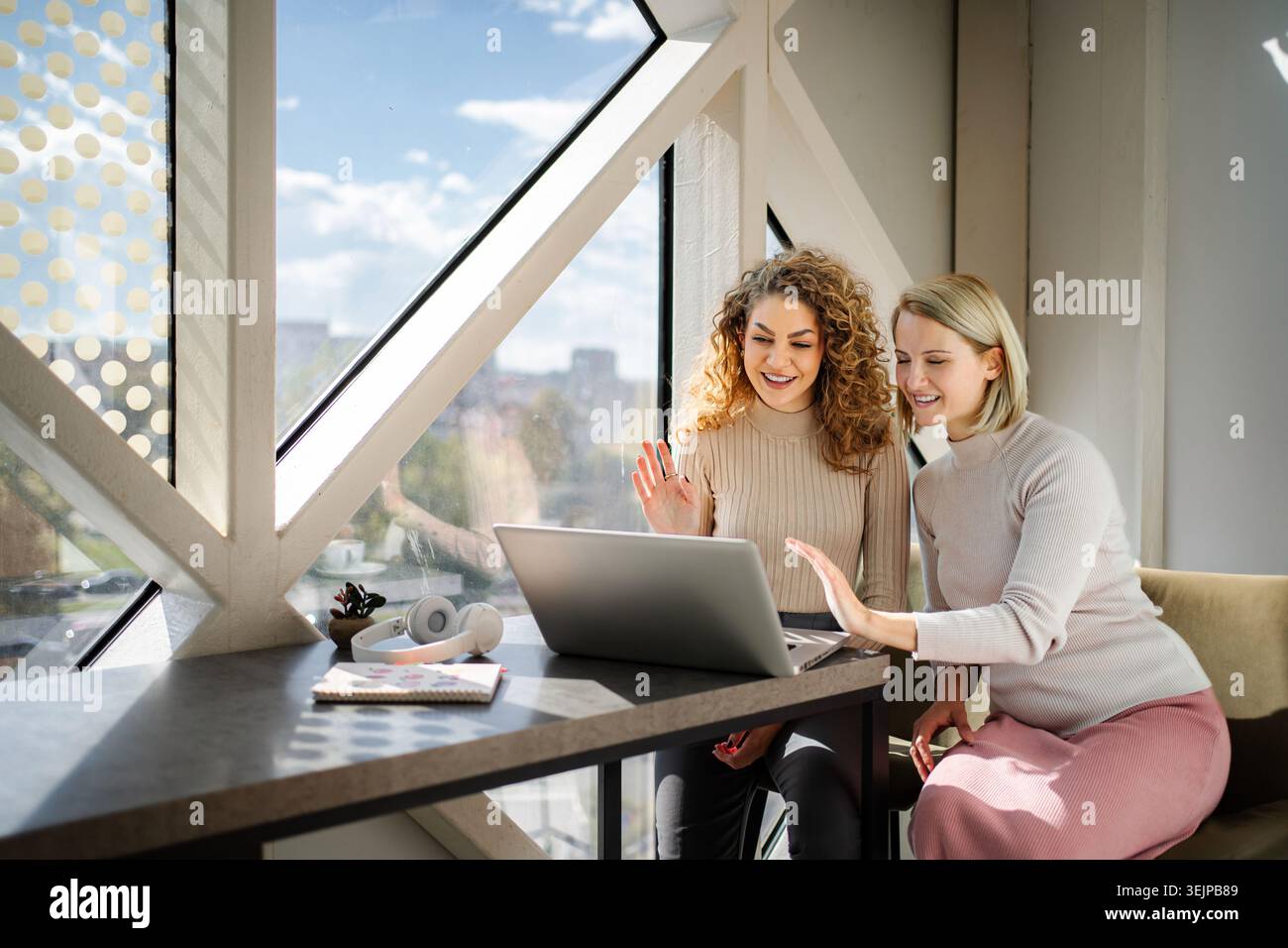 Deux femmes appelant vidéo sur ordinateur portable agitant les mains Banque D'Images