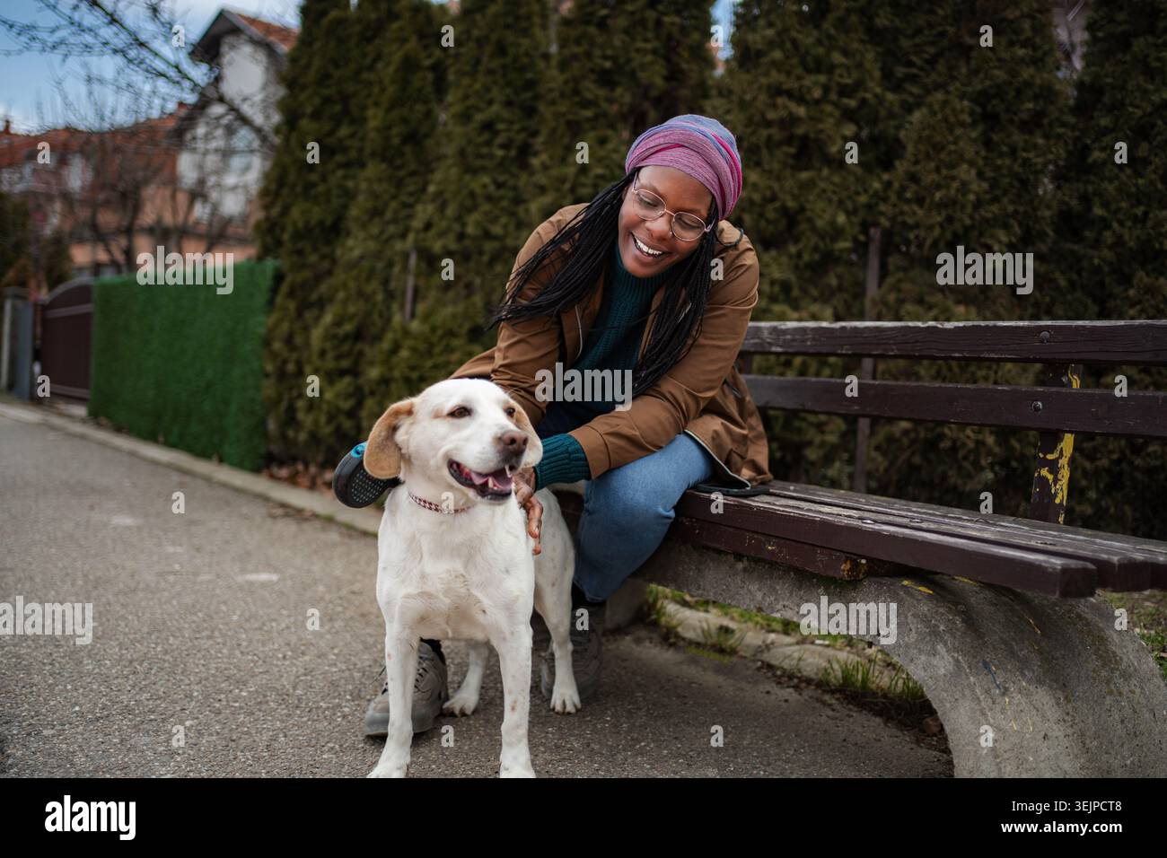 Heureuse jeune femme adulte caressant chien dans le parc Banque D'Images