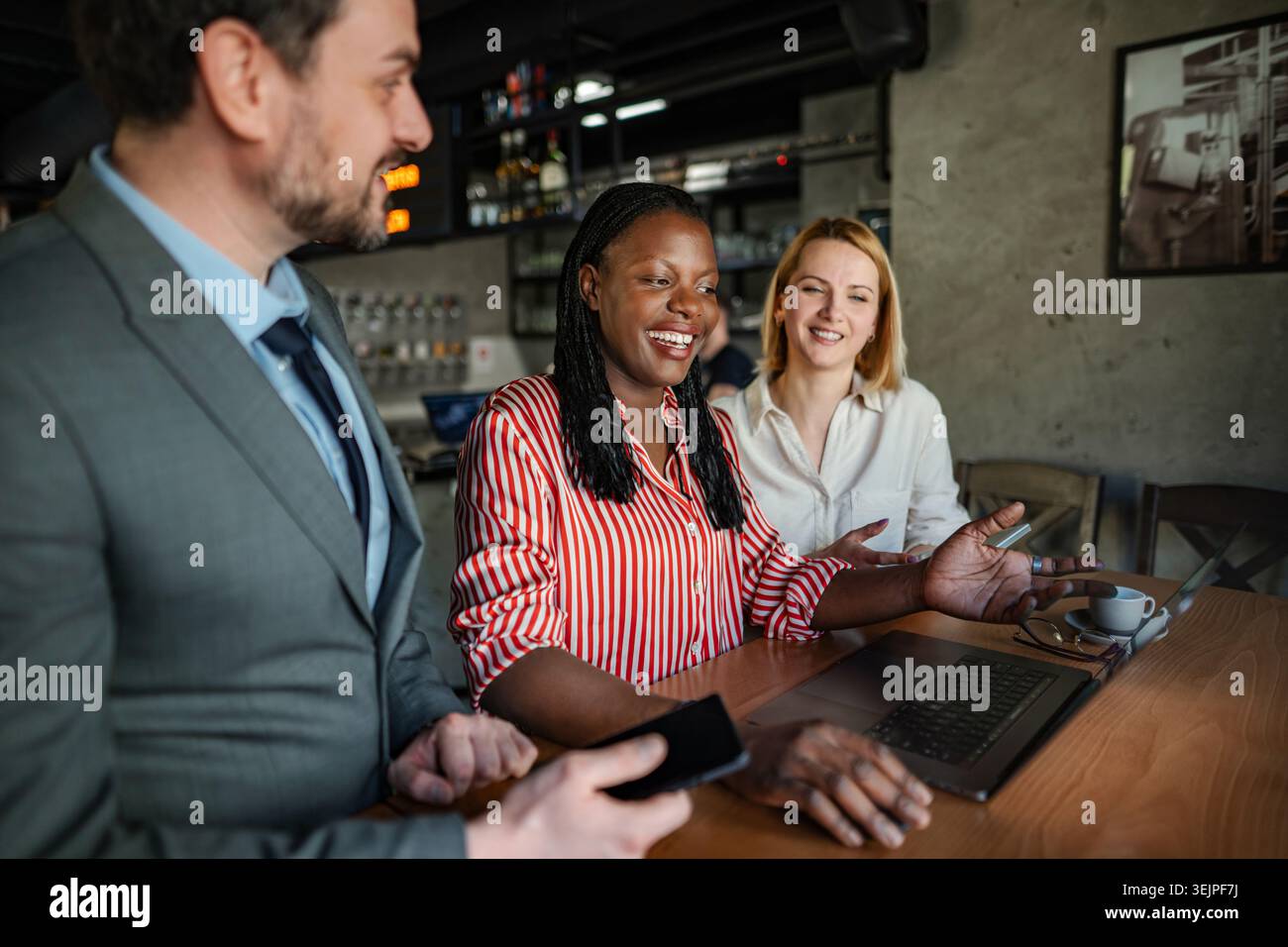 Équipe d'affaires diversifiée collaborant sur ordinateur portable dans un café Banque D'Images