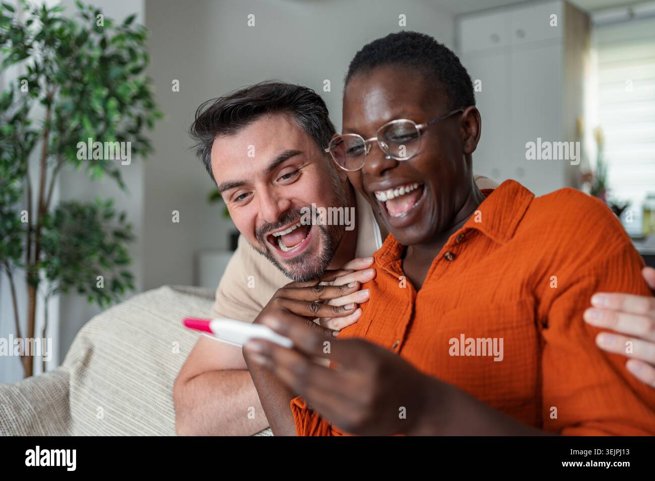 Couple interracial heureux regardant le résultat positif du test de grossesse Banque D'Images