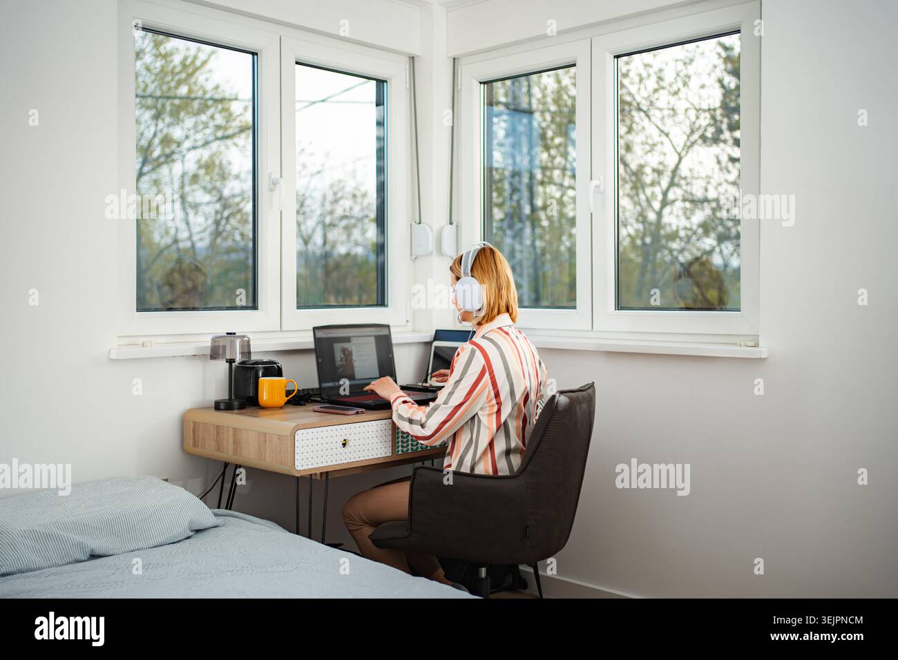 Femme travaillant à domicile à l'aide d'un ordinateur portable et d'un casque Banque D'Images