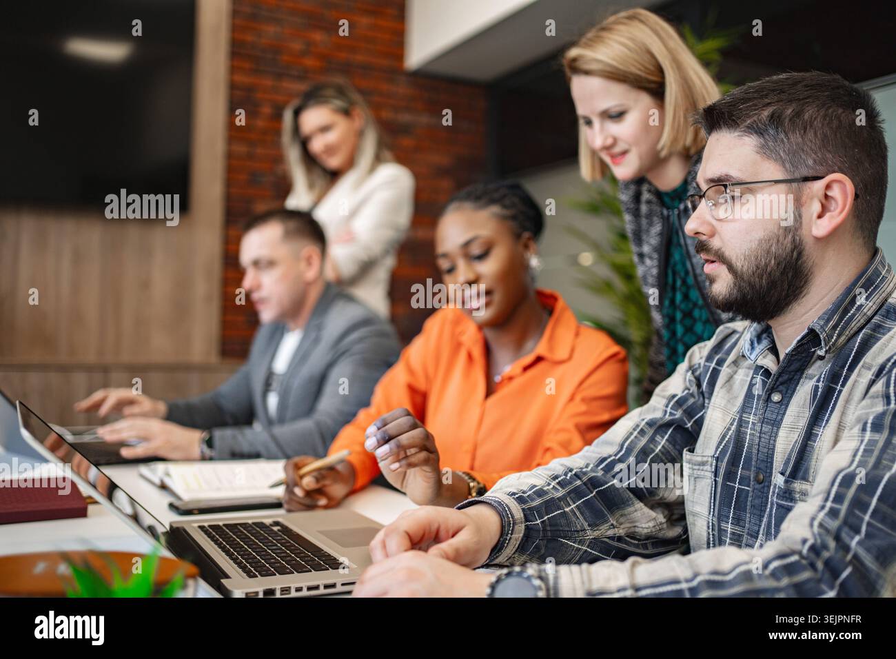 Groupe de personnes assis à une table avec des ordinateurs portables Banque D'Images