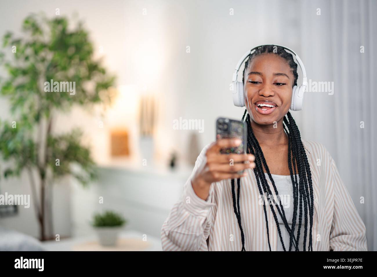 Jeune femme noire appréciant la musique naviguant sur smartphone Banque D'Images