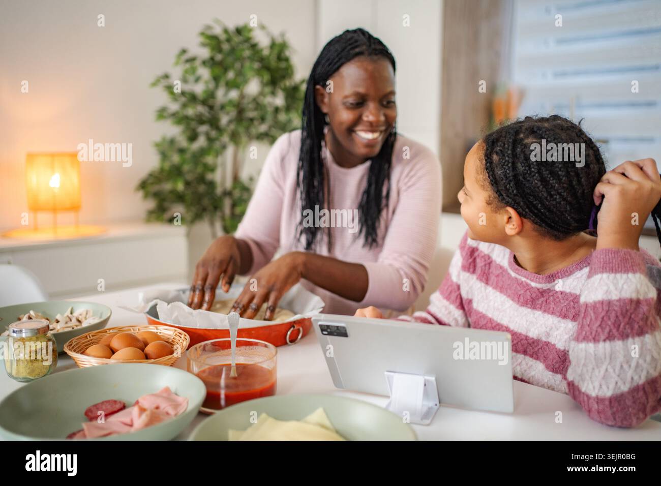 Mère et fille cuisinant la préparation de pizza à l'aide d'une tablette numérique à la maison Banque D'Images