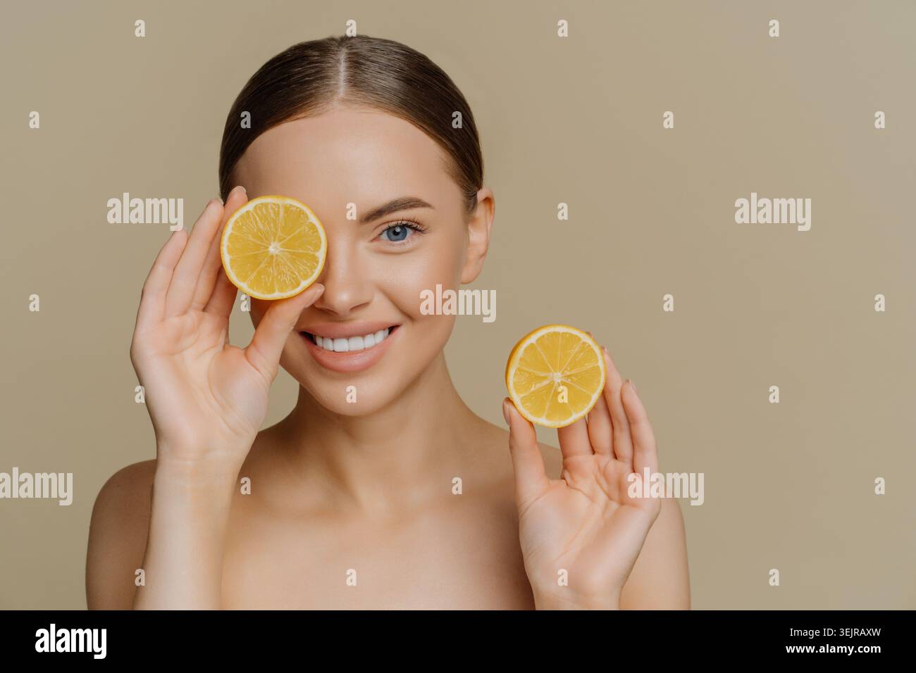 Femme souriante tenant des tranches de citron dans le portrait naturel de beauté de soin de la peau Banque D'Images