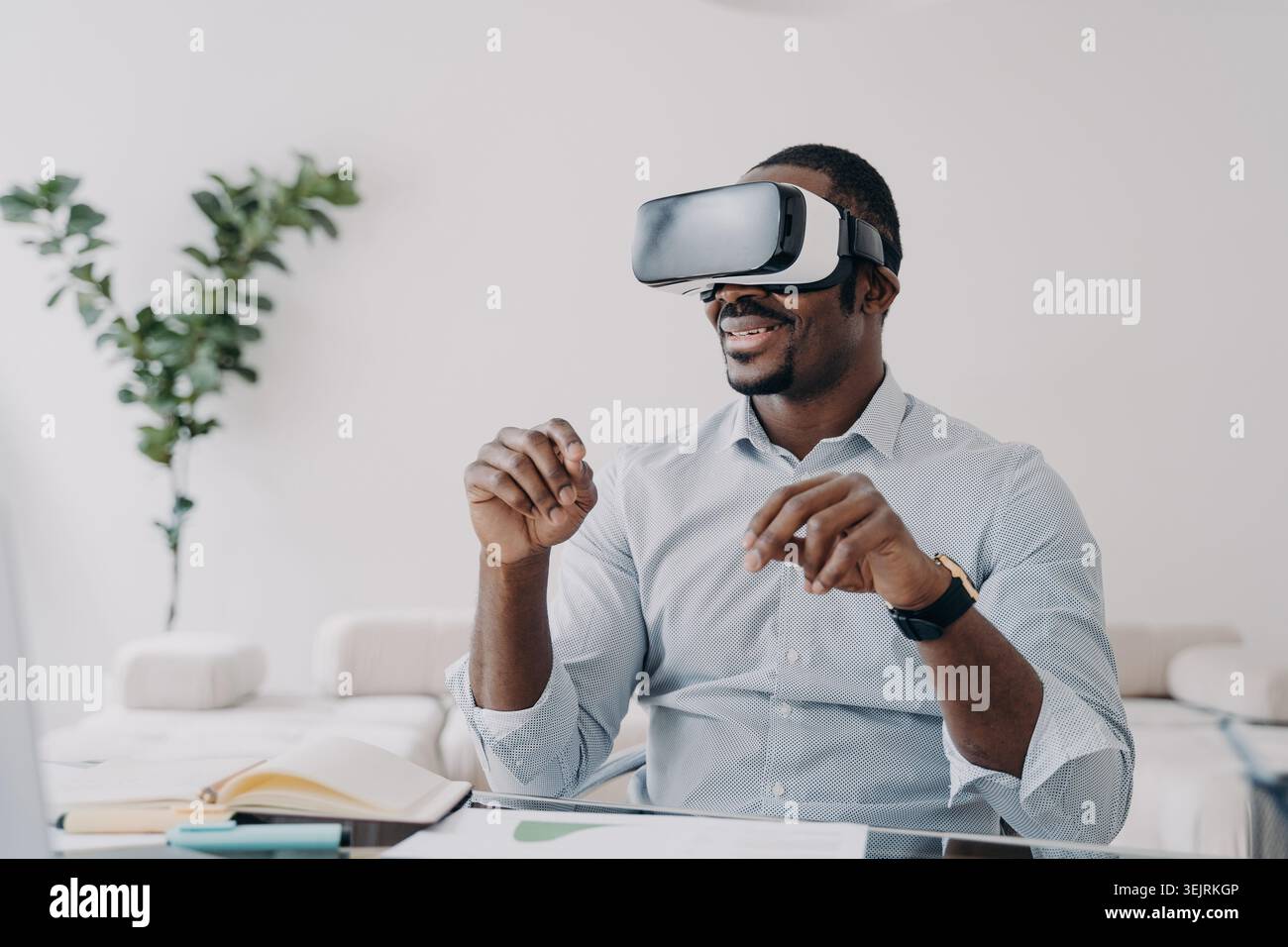 Homme portant des gestes de casque de réalité virtuelle avec les mains au bureau dans le bureau à domicile moderne Banque D'Images