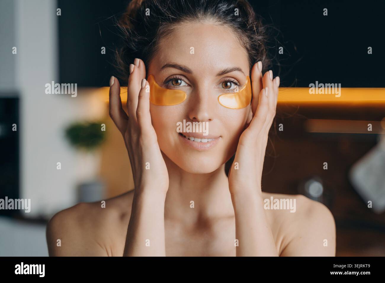 Jeune femme appliquant sous les patchs oculaires pendant la routine de soin de la peau à la maison Banque D'Images