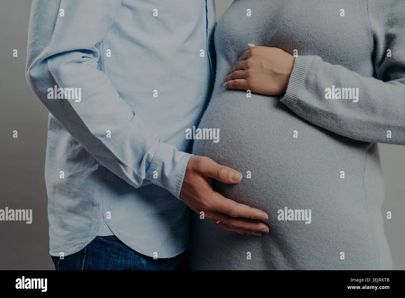 Le couple attendu tient doucement le ventre enceinte ensemble dans la maternité intime en gros plan Banque D'Images