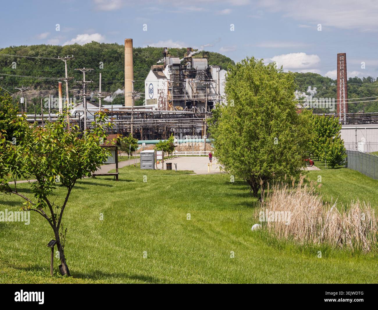 Clairton Pennsylvanie USA-05 10 2026 : L'infrastructure de fabrication d'acier massive de l'usine de coke de Clairton émet de la vapeur derrière le champ vert Banque D'Images