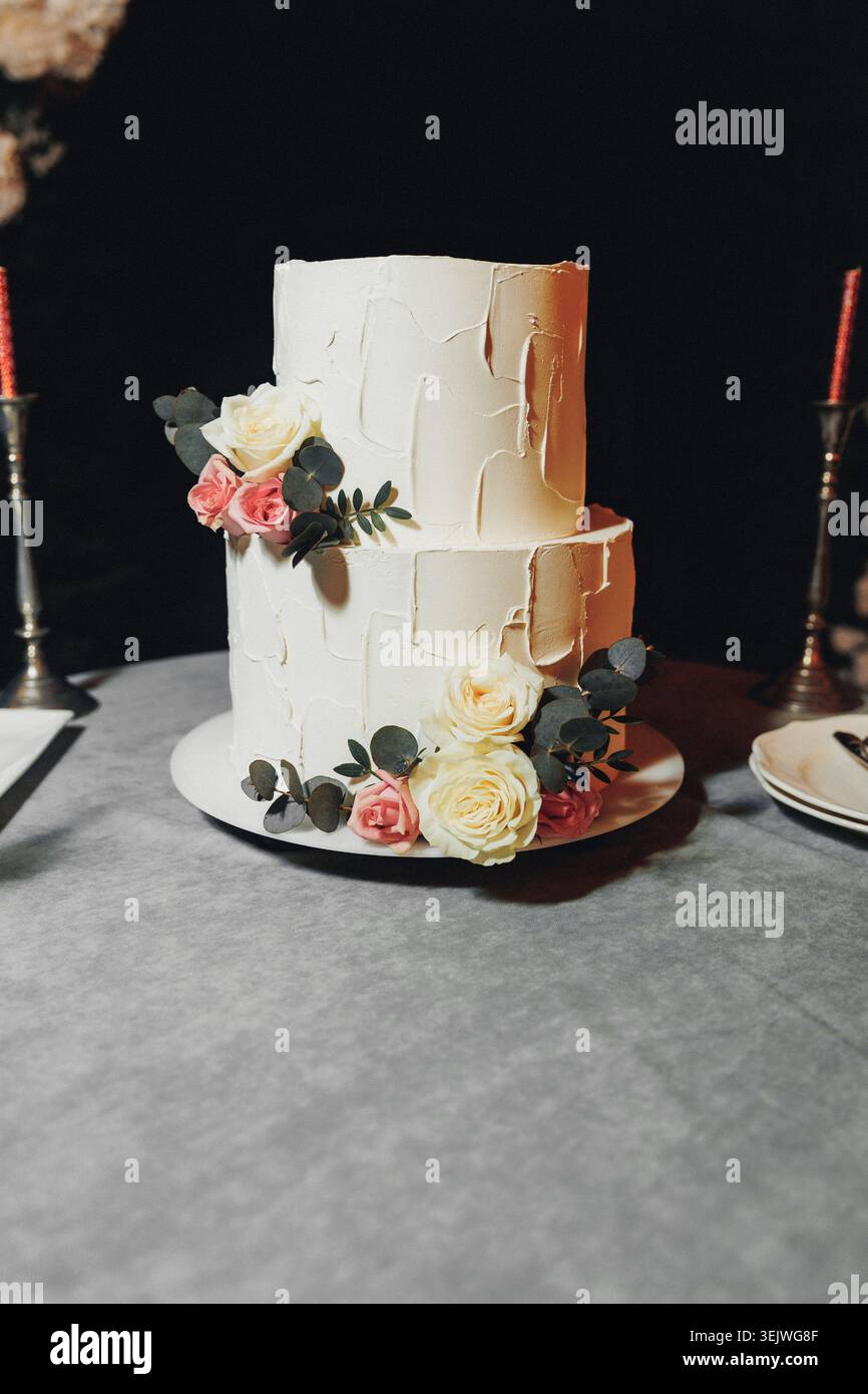 Gâteau texturé blanc avec des roses douces et de la verdure Banque D'Images