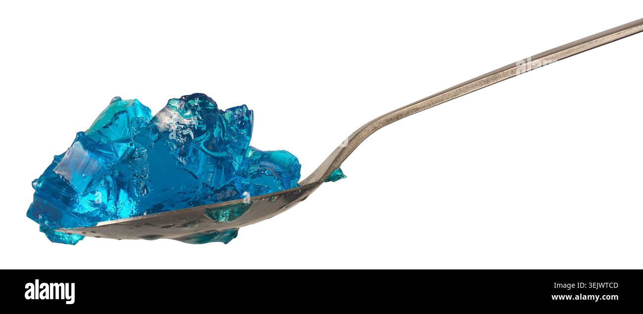 morceaux de gelée de gélatine bleue translucide sur cuillère en métal argenté fond blanc isolé, dessert à texture humide brillante, vue de côté Banque D'Images