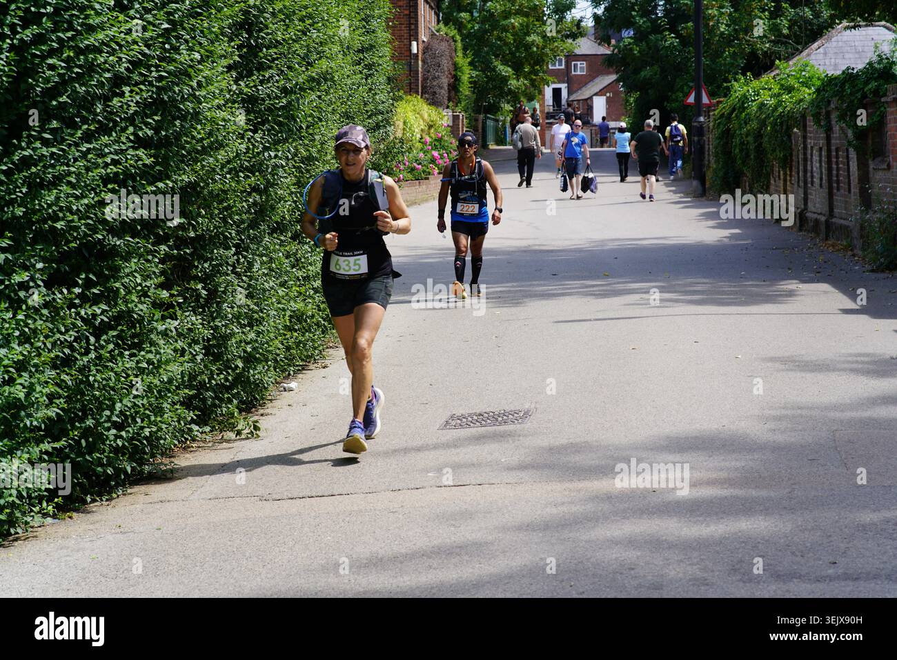 Coureuse féminine menant lors de la course sur route de Tonbridge sur une rue ensoleillée bordée d'arbres, action dynamique prise avec d'autres concurrents derrière.Tonbridge, Kent Banque D'Images