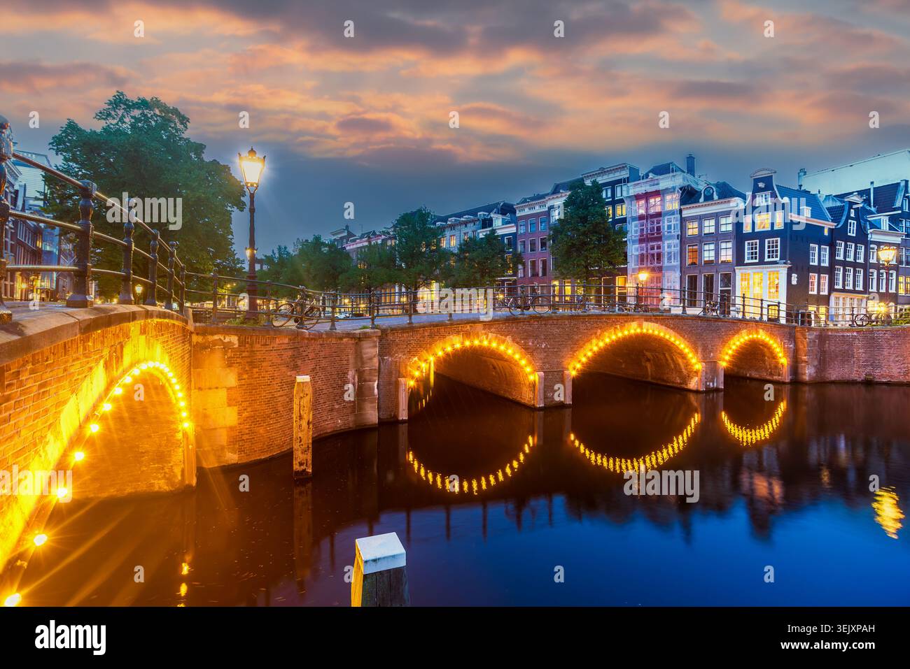 Ponts du canal d'Amsterdam illuminés au coucher du soleil, vue panoramique à l'heure bleue du Reguliersgracht et des maisons hollandaises traditionnelles sans personnes, pays-Bas Banque D'Images