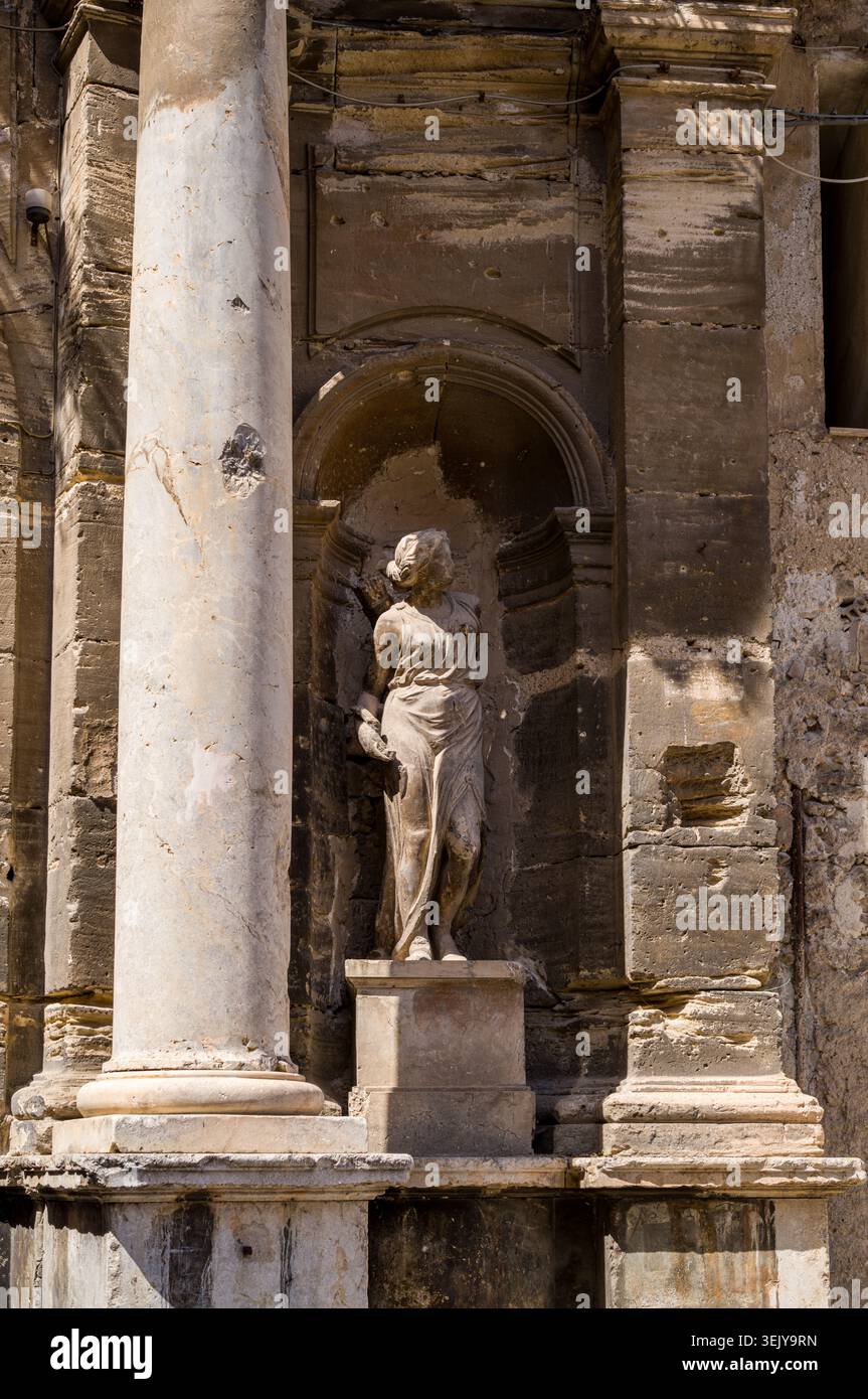 Une statue en pierre classique d'une femme gracieuse se dresse dans une niche en pierre entre les colonnes. La figure sert d'élémen architectural ornemental Banque D'Images