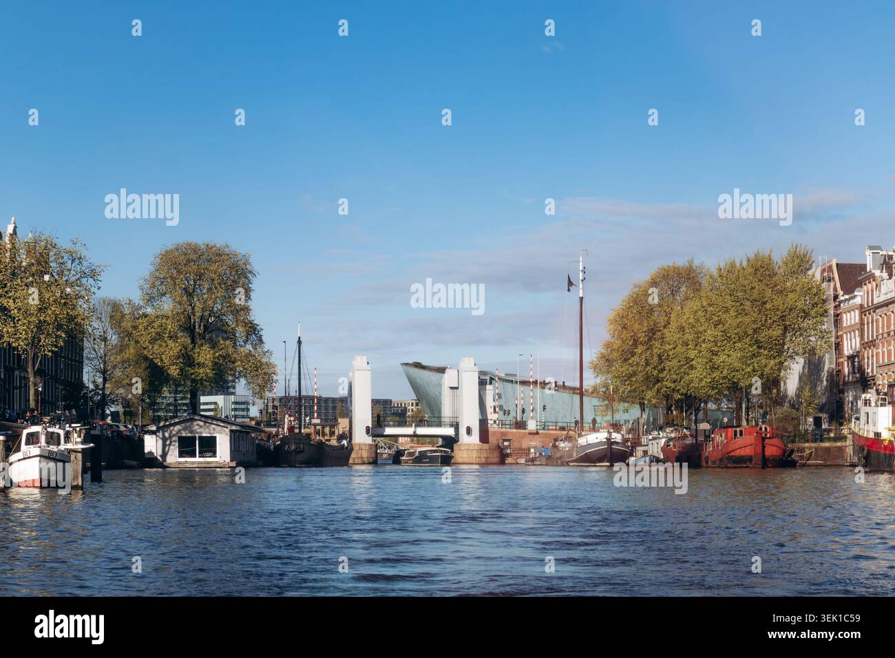 Amsterdam, pays-Bas - 18 avril 2026 : canal Oosterdok avec bateaux et pont Oosterdoksebrug près du musée des sciences NEMO à Amsterdam par un printemps ensoleillé Banque D'Images