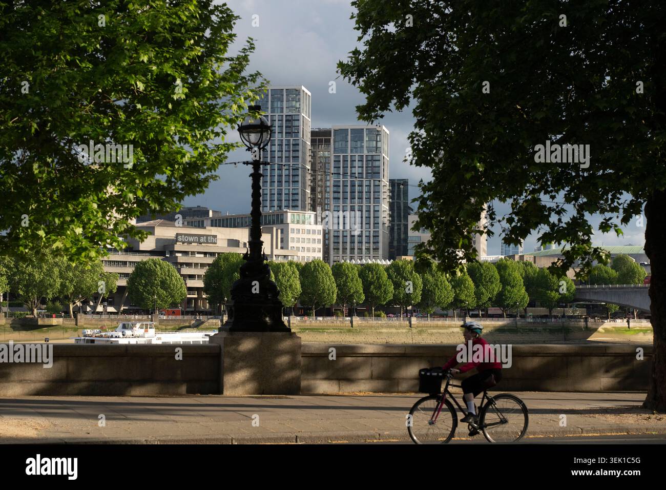 Un cycliste longe la rive nord de la Tamise à Londres, avec le Royal Festival Hall et South Bank place en arrière-plan. Banque D'Images