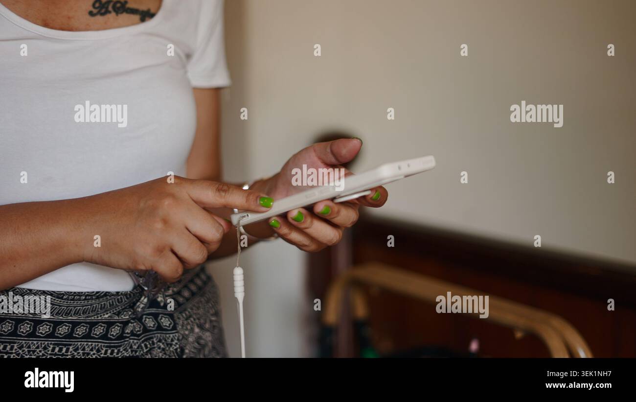 Personne naviguant sur smartphone, connectant des écouteurs filaires, profitant du contenu numérique Banque D'Images