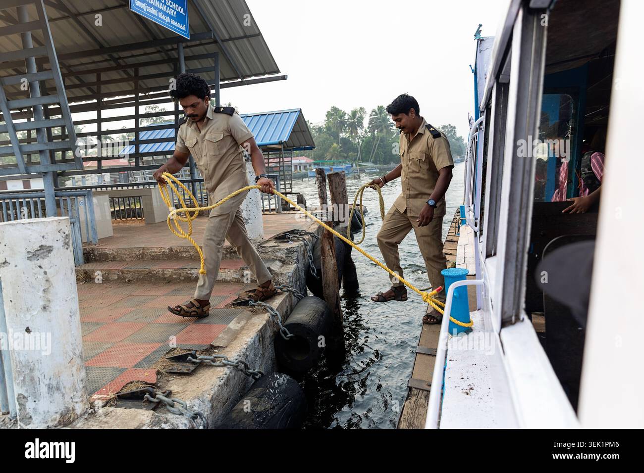 Membres de l'équipage de ferry en uniformes kaki manipulant des cordes d'amarrage alors qu'un bateau public à passagers arrive à une jetée, Alleppey (Alappuzha), Kerala, Inde Banque D'Images