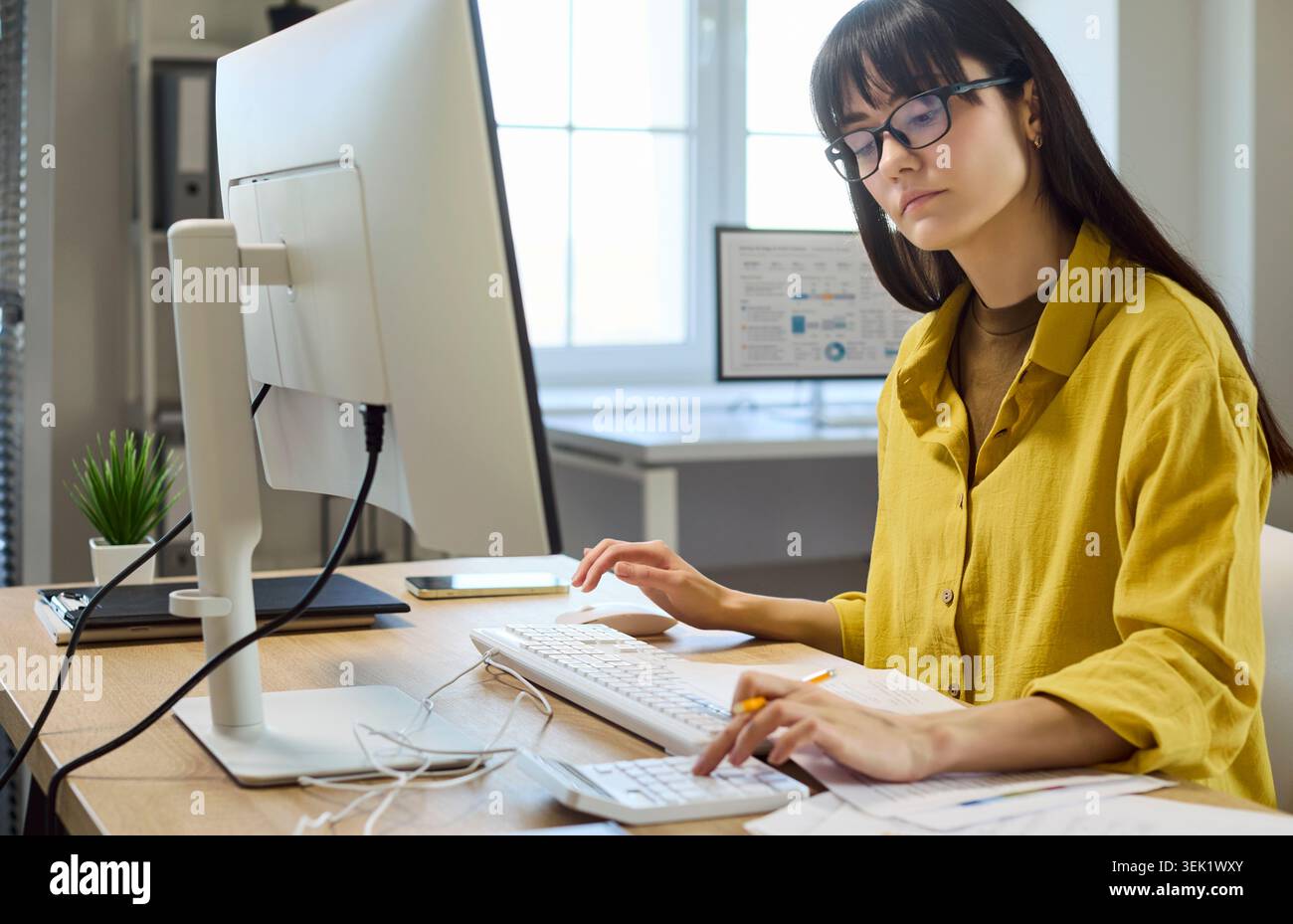 Femme focalisée faisant la budgétisation financière à l'ordinateur avec calculatrice dans le bureau moderne Banque D'Images