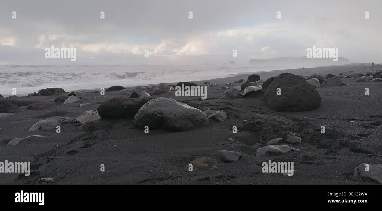 De puissantes vagues s'écrasent sur les sables volcaniques noirs de la plage de Reynisfjara près de Vík í Mýrdal, en Islande, avec l'emblématique cheminée de Reynisdrangar qui s'élève Banque D'Images