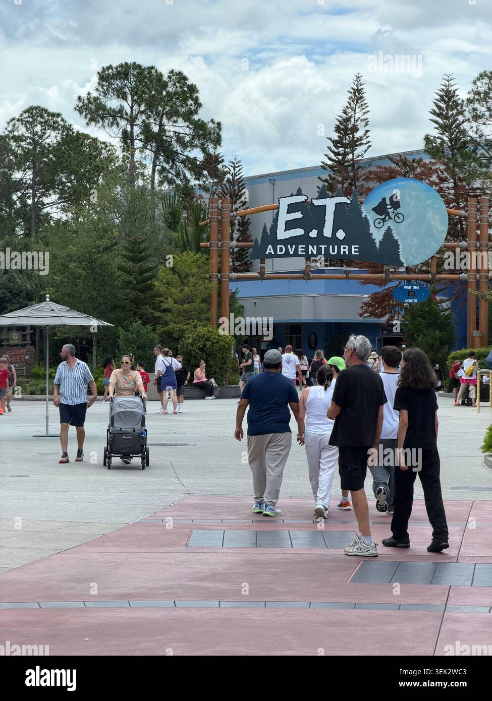 ORLANDO, FL - 1er JUIN 2026 : une foule de touristes du parc à thème marche le long d'un sentier pavé vers le panneau emblématique et Adventure Ride la nuit. - Image de stock capturée avec un smartphone
