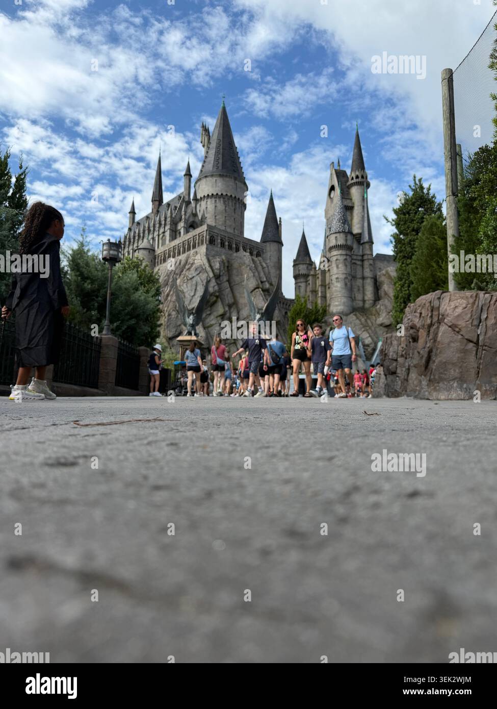 ORLANDO, FL - 31 mai 2026 : vue à angle bas des touristes du parc à thème marchant le long d'un sentier depuis le château de Poudlard à Islands of Adventure. - Image de stock capturée avec un smartphone