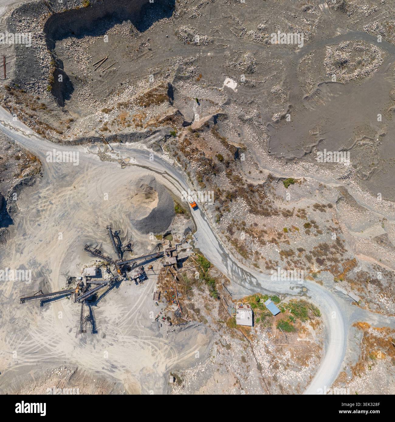 La vue aérienne capture un vaste site industriel de carrière au Kirghizistan. Les chemins de terre sinueux et les machines industrielles mettent en valeur les terrains accidentés et l'activité. Banque D'Images