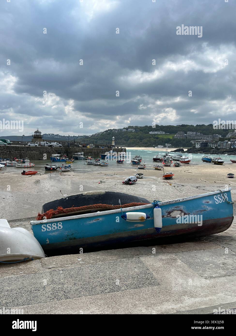 Bateaux sur la plage du port avec vue sur le phare de St Ives, Cornouailles, Angleterre, Royaume-Uni. - Image de stock capturée avec un smartphone