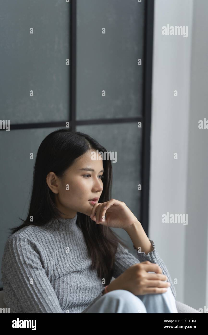 Jeune femme asiatique se sent seule, triste, malade, stressée, seule à la maison sur le canapé pour profiter du mode de vie de bien-être dans les soins de santé Banque D'Images