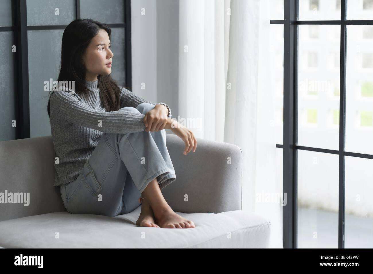 Jeune femme asiatique se sent seule, triste, malade, stressée, seule à la maison sur le canapé pour profiter du mode de vie de bien-être dans les soins de santé Banque D'Images