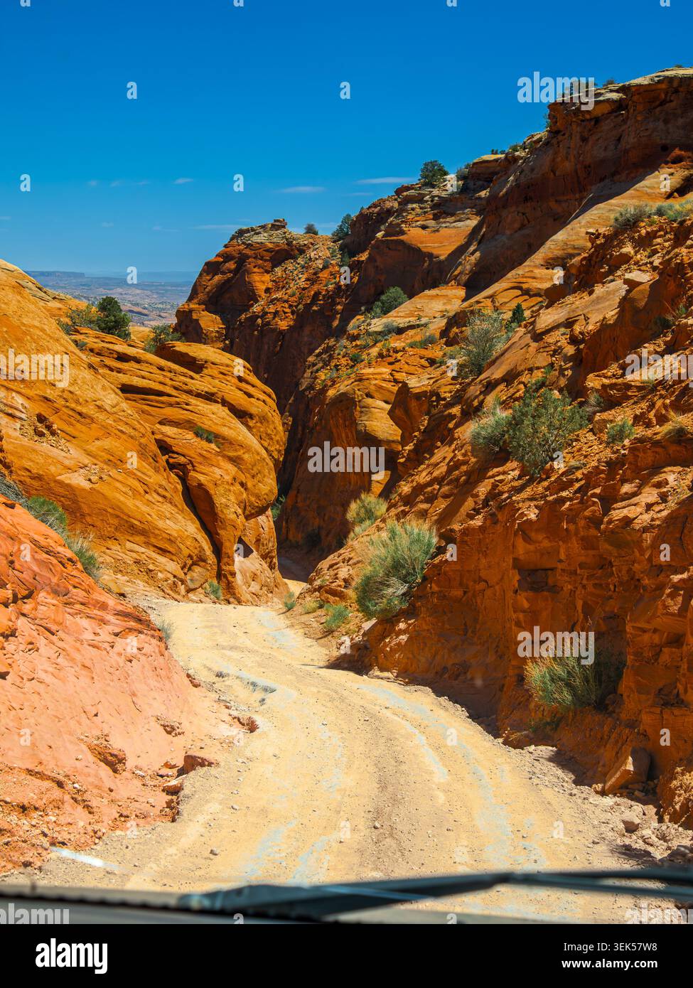 Moab, Utah 15 mai 2026 le chemin de terre dans les Canyonlands de Moab mène à travers une étroite brèche dans les falaises de grès rouge Banque D'Images