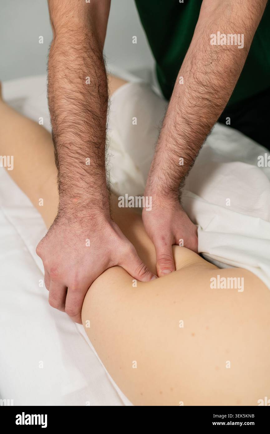 Thérapeute professionnel effectuant un massage des tissus profonds sur la cuisse du client pendant le traitement de bien-être. Thérapie manuelle axée sur la récupération musculaire, la tension re Banque D'Images