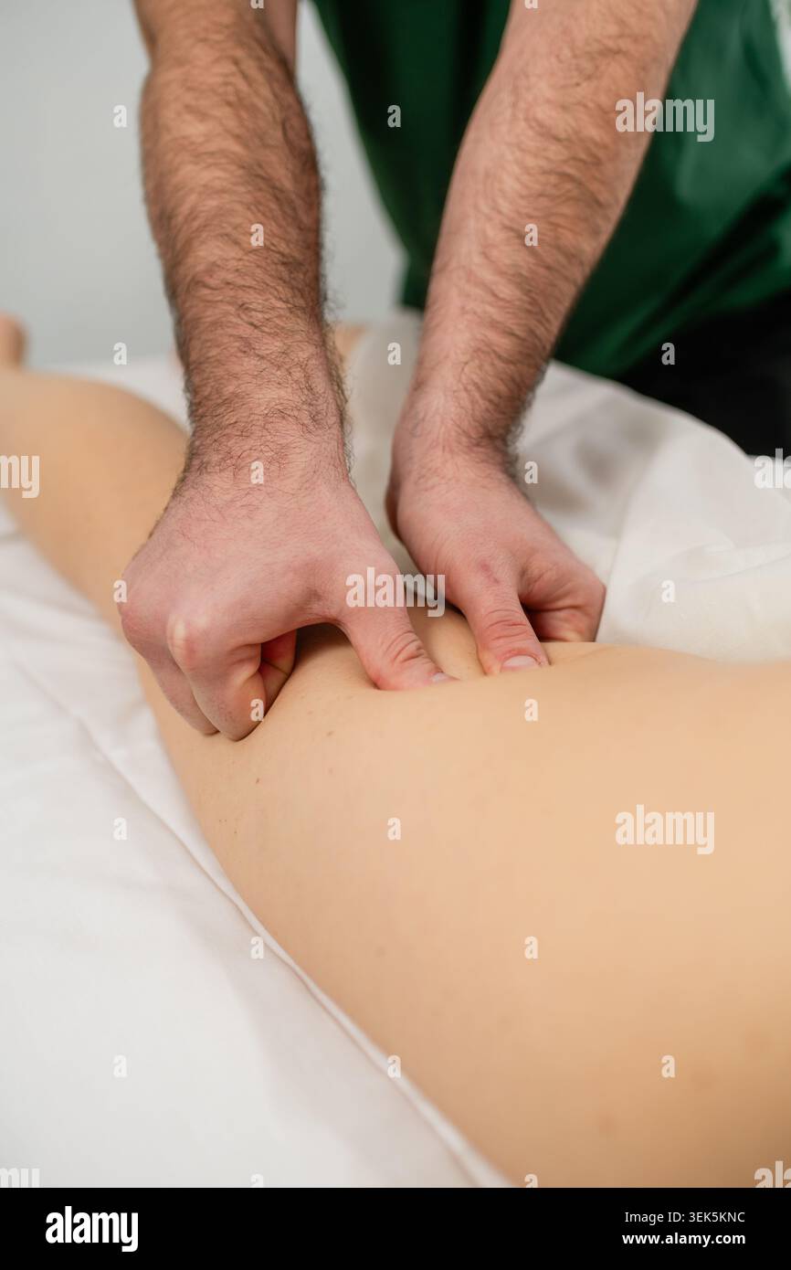 Thérapeute professionnel effectuant un massage des tissus profonds sur la cuisse du client pendant le traitement de bien-être. Thérapie manuelle axée sur la récupération musculaire, la tension re Banque D'Images