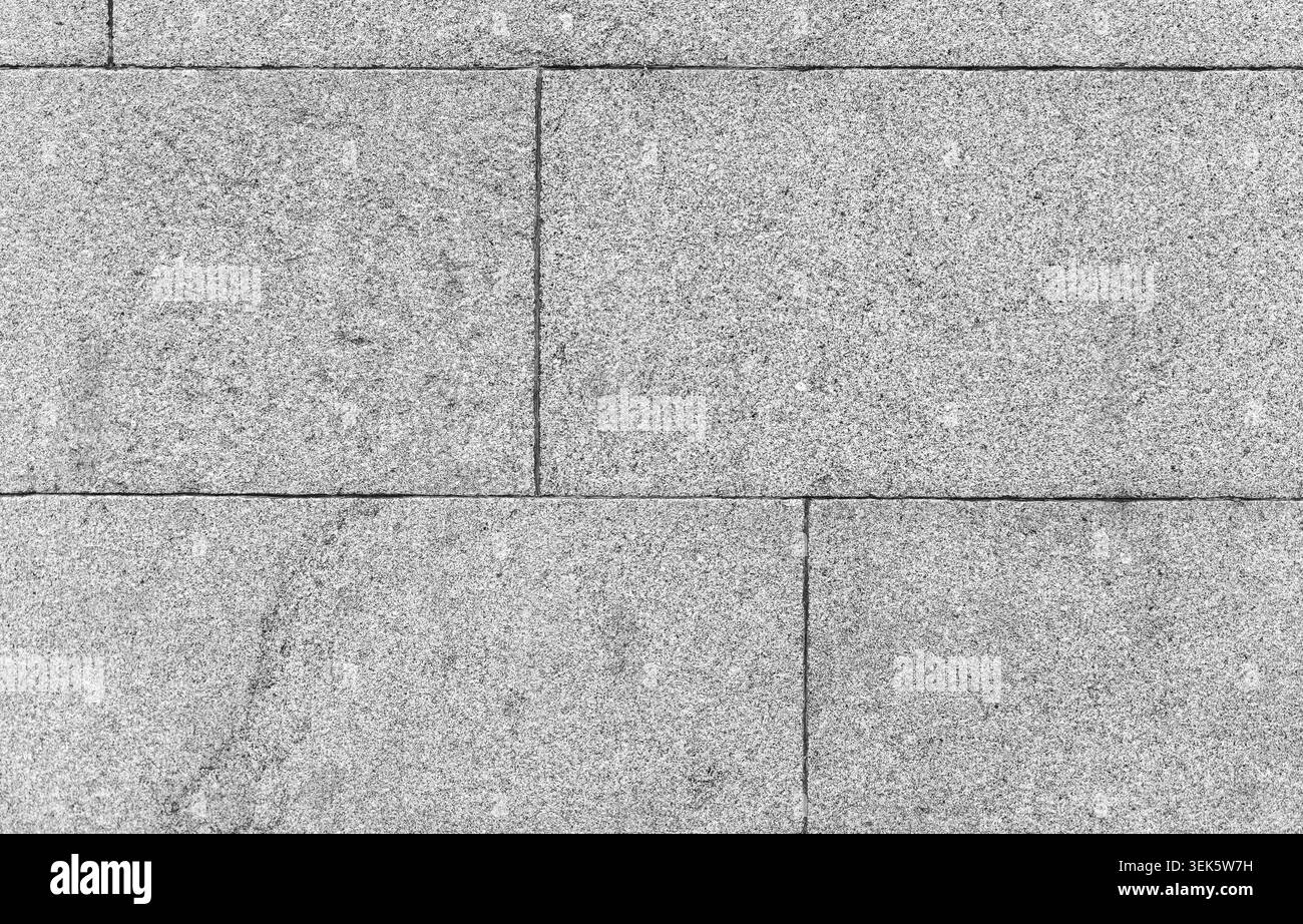 Gros plan d'un mur de granit gris fait de blocs de pierre rectangulaires montrant le grain fin, les coutures et les intempéries subtiles ; une surface architecturale propre idéale Banque D'Images