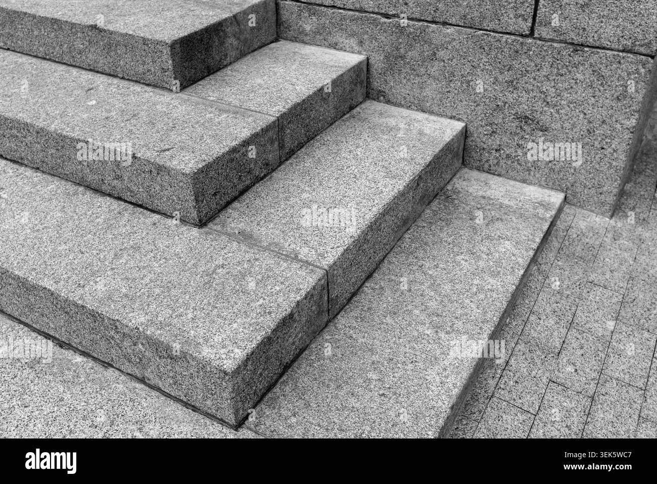 Vue rapprochée de marches de granit en noir et blanc mettant en évidence des lignes géométriques nettes, une texture de pierre brute et une architecture urbaine minimaliste Banque D'Images