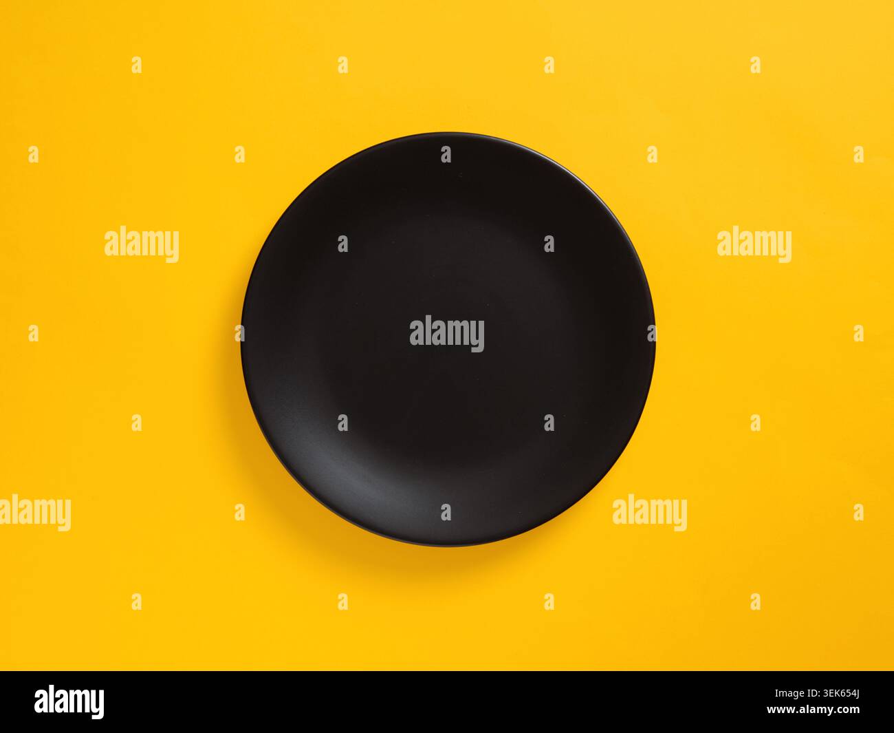 Plaque noire sur fond jaune, composition minimaliste offrant un espace de copie pour des thèmes culinaires ou design Banque D'Images