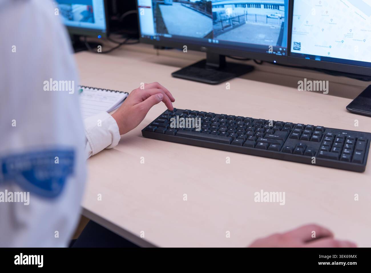 Gros plan d'une responsable de la sécurité ou d'un gardien en uniforme qui rédige des notes et remplit une feuille de rapport d'incident ou un journal de bord quotidien à son bureau Banque D'Images