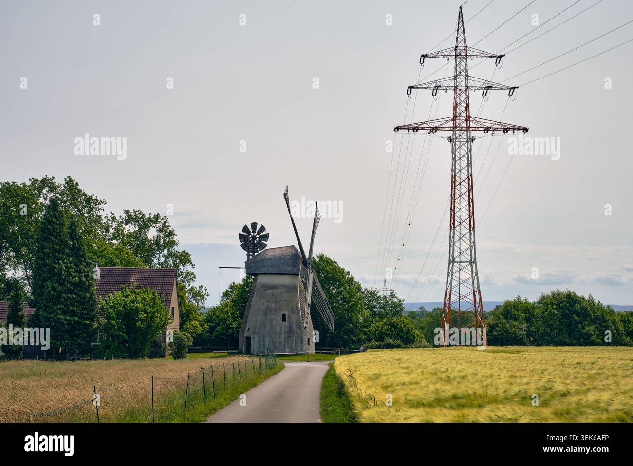 Paysage de la transition énergétique : moulin à vent historique et mât électrique moderne à Minden, Allemagne Banque D'Images