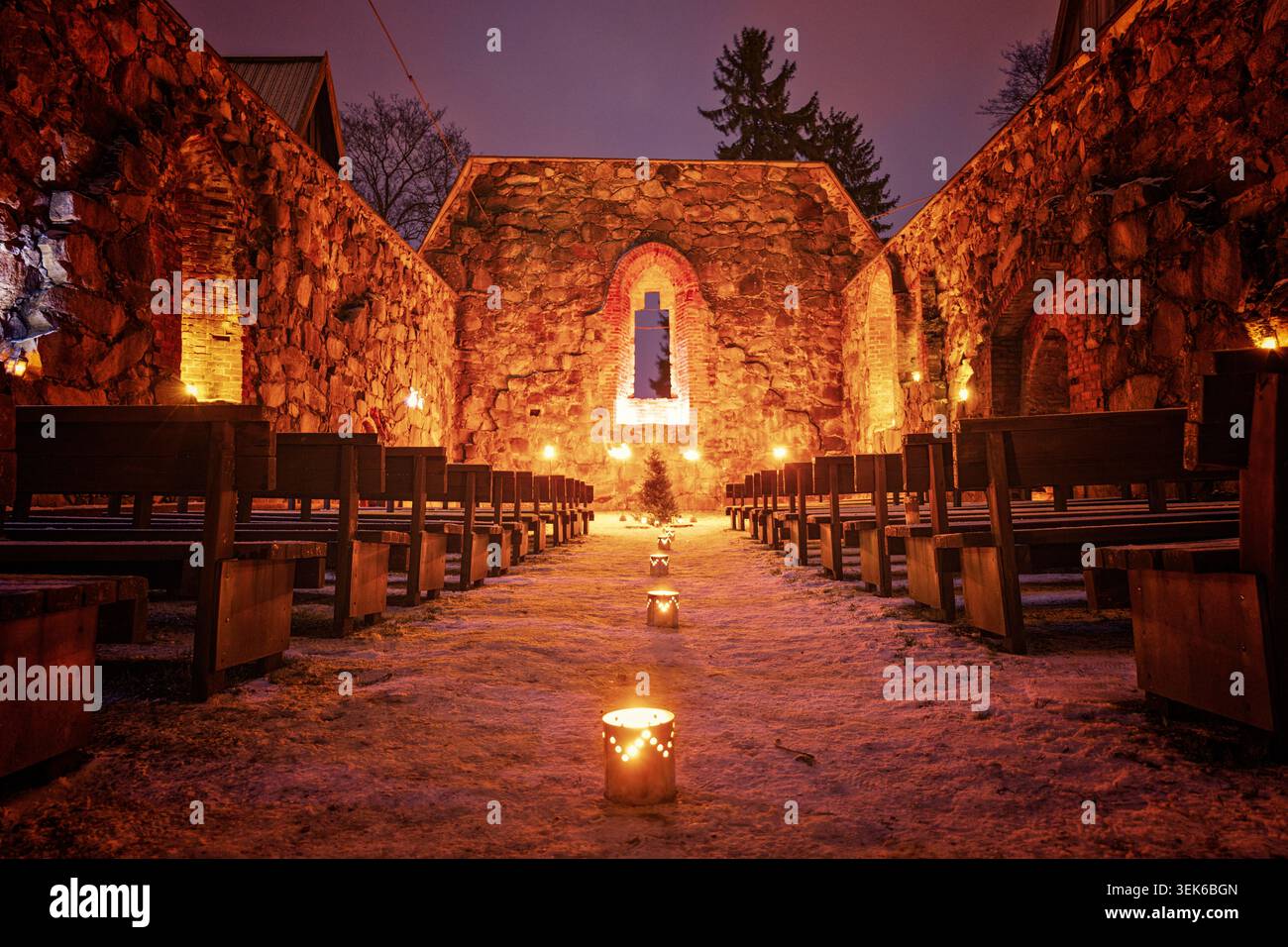 Pälkäne, Finlande - 25 décembre 2020 : scène de Noël festive dans des ruines historiques avec des bougies allumées, un sol enneigé et des sièges en bois rustiques Banque D'Images