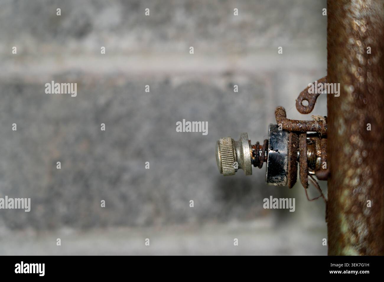 Gros plan détaillé d'un vieux bouton mécanique usé avec mécanisme à ressort et fixations en fil rouillé. L'objet s'étend à partir de la droite s. Banque D'Images