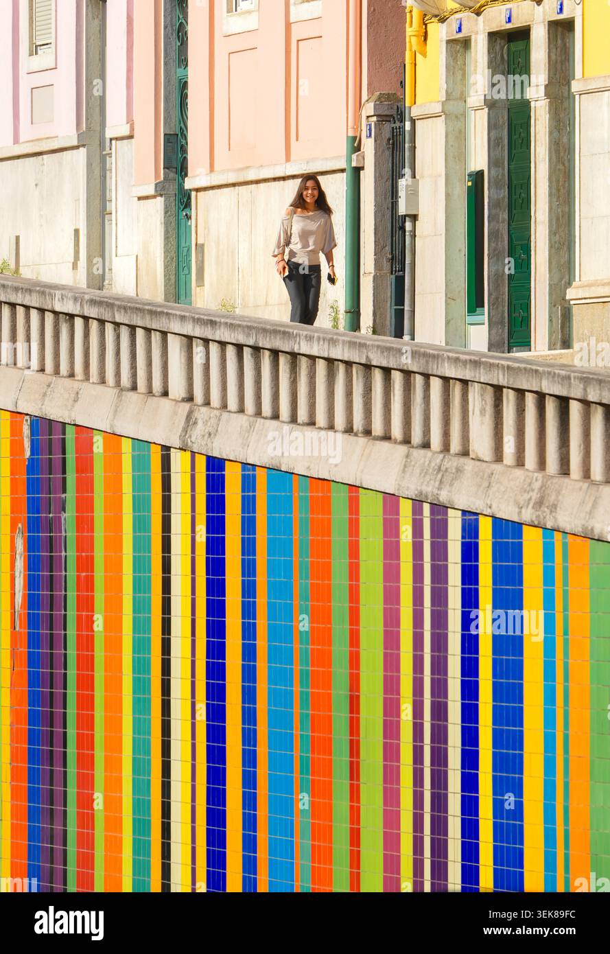 Le mur carrelé coloré contraste les façades de maison traditionnelles, femme marchant, Av. Infante Santo, Lisbonne, Portugal – photographie de rue urbaine Banque D'Images