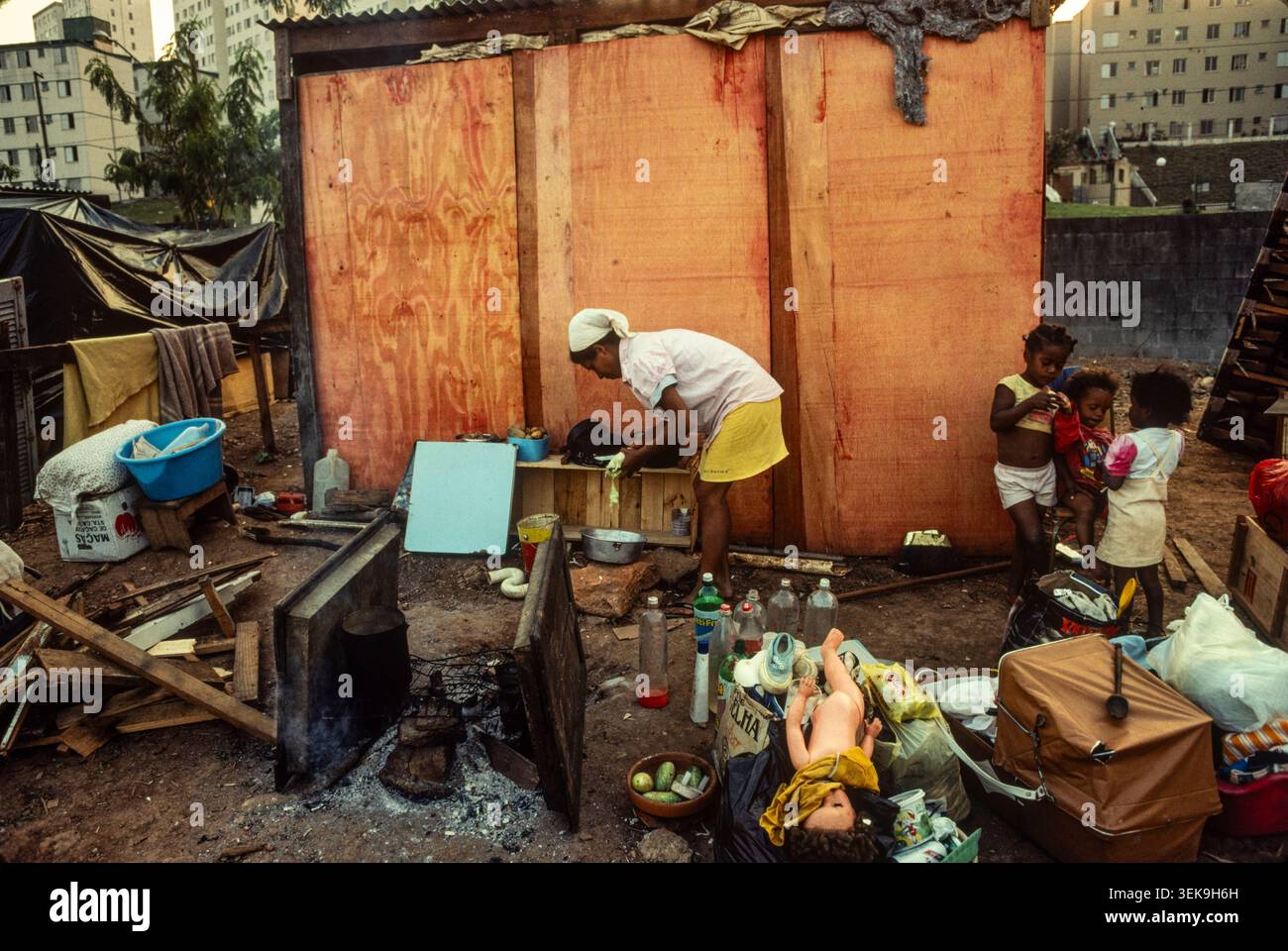 Sao Paolo, Brésil, 1991 : une mère prépare de la nourriture pour ses enfants dans leur maison temporaire sur des terres squattées dans cette invasion de terres. Ils ont été expulsés peu de temps après. Banque D'Images