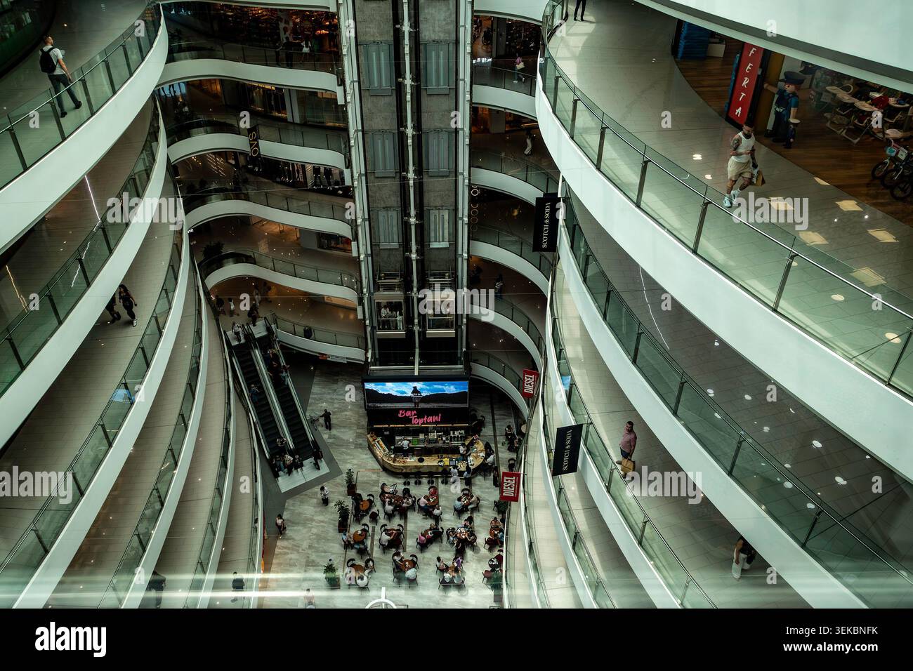 Intérieur du centre commercial Toptani à Tirana, Albanie, avec balcons incurvés, balustrades en verre, escaliers mécaniques, et une cage d'ascenseur centrale. Banque D'Images