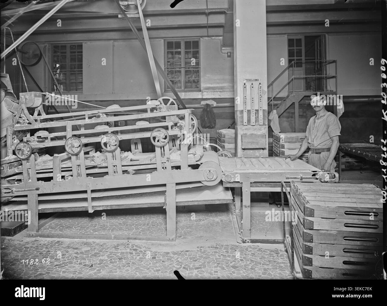 Une photographie de presse de l’Agence Rol enregistre une machine de façonnage de pâte à la boulangerie assistance publique à Paris en 1927. L'image documente la production de pain et les opérations de boulangerie mécanisées au sein d'une grande installation institutionnelle de préparation des aliments. Banque D'Images