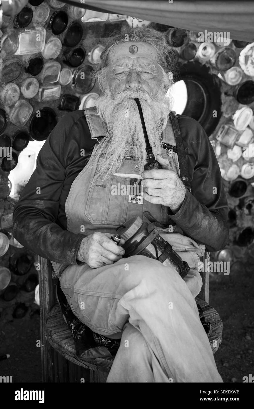 Un résident et artiste de longue date, connu uniquement sous le nom de Magicien, fume sa pipe. Jésus est dans la communauté informelle des artistes de Slab City, près du Salto Banque D'Images