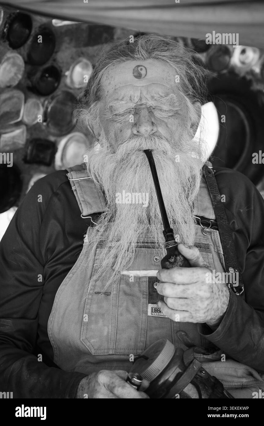 Un résident et artiste de longue date, connu uniquement sous le nom de Magicien, fume sa pipe. Jésus est dans la communauté informelle des artistes de Slab City, près du Salto Banque D'Images