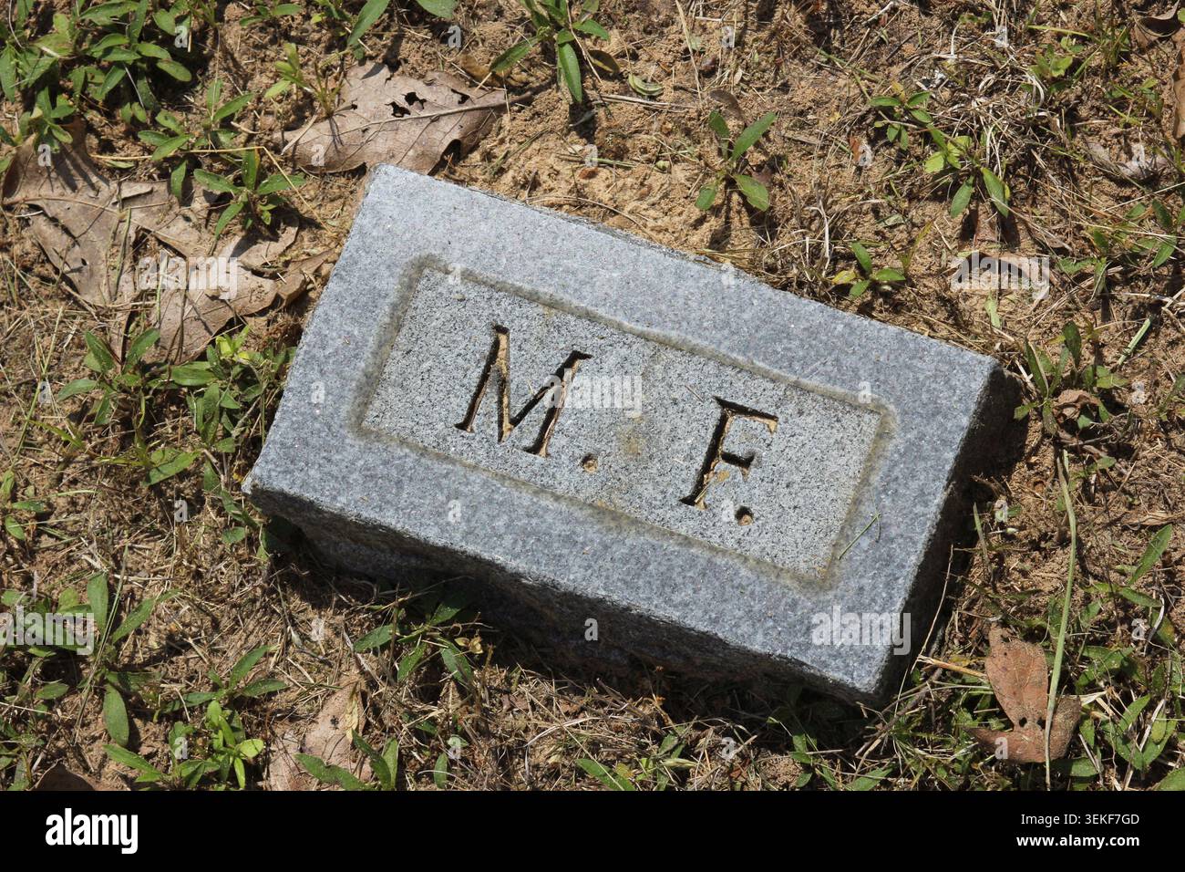 Pierre de brique dans le cimetière avec lettres MF gravées Banque D'Images