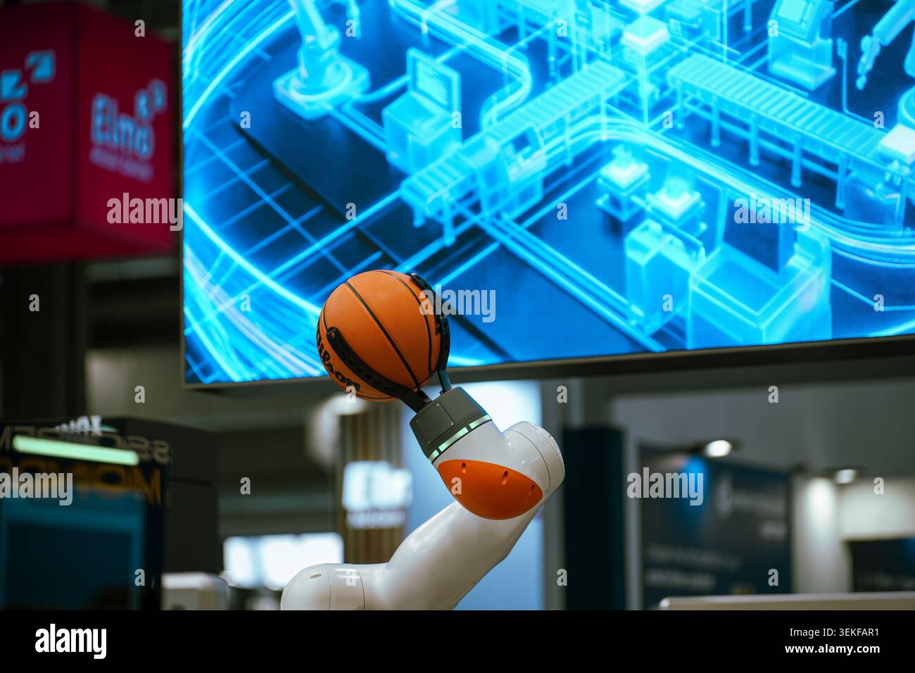 Un bras robotique collaboratif blanc et orange utilise une pince à griffes mécanique spécialisée pour tenir un ballon de basket officiel de la NBA lors d'un démon technologique Banque D'Images