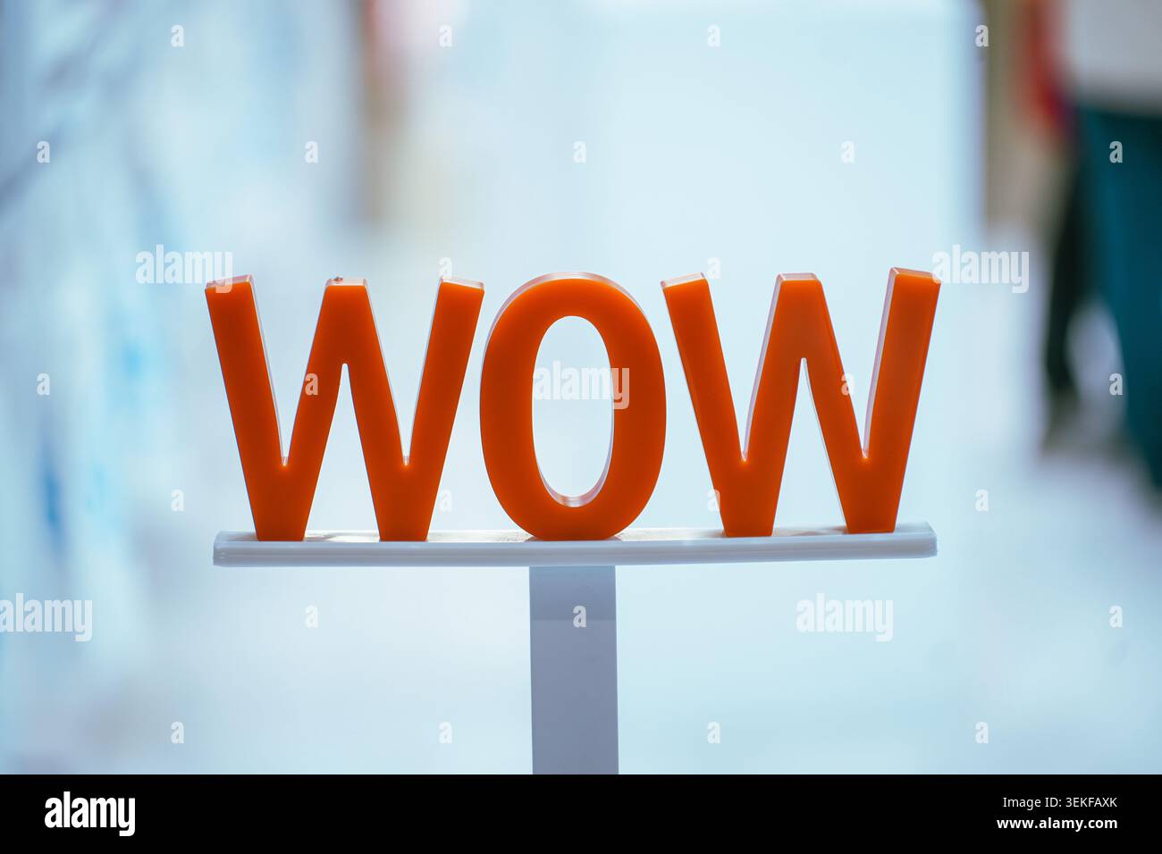 Lettres orange 3D orthographiant 'WOW' sur un stand blanc lors d'un salon. Banque D'Images