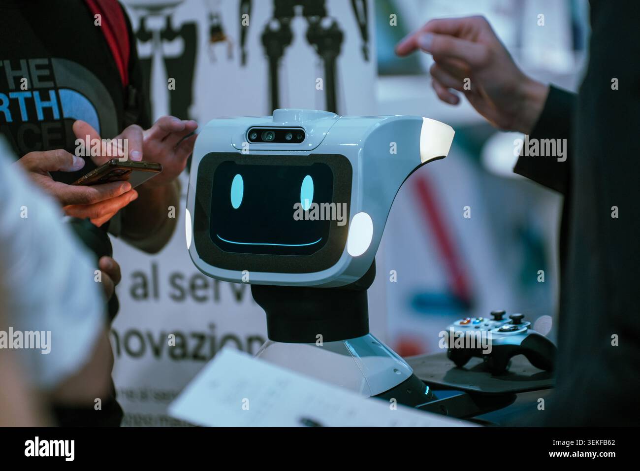 Un robot de service interactif avec un affichage numérique de visage souriant est présenté lors d'une démonstration de produit lors d'un salon d'automatisation industrielle, comme vis Banque D'Images